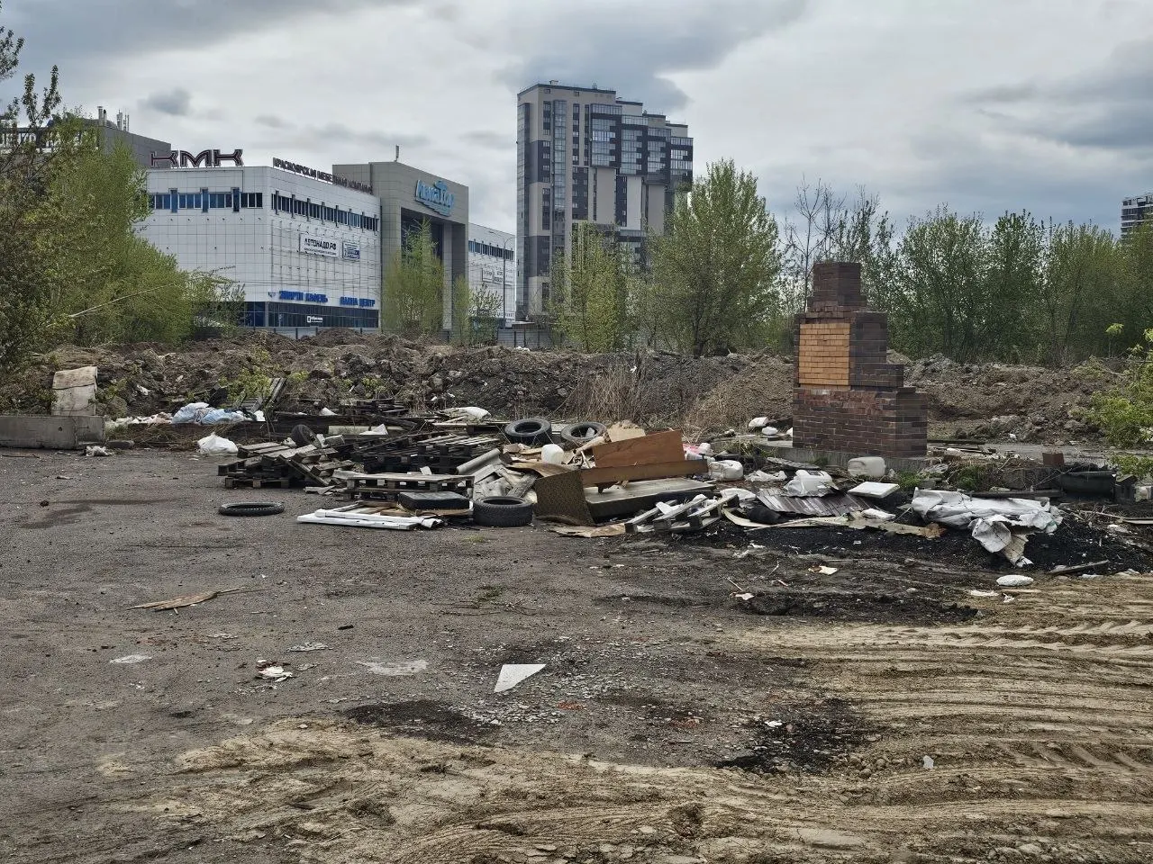 После демонтажа шиномонтажек, кафе и павильонов на Авиаторов на месте остался строительный мусор, покрышки и коммунальные отходы. Из‑за отсутствия ограждений пыль и торчащая арматура угрожают жителям, уборку планируют оплачивать из бюджета.