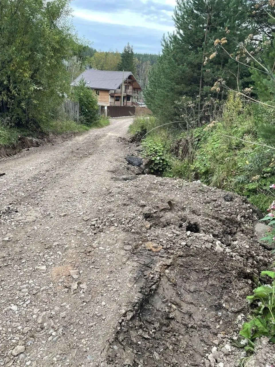Размытая дорога в поселке под Красноярском засыпана смесью, похожей на строительные отходы, якобы в рамках срочного ремонта за счёт бюджета. Жители опасаются последствий для ливневки и водоотвода.